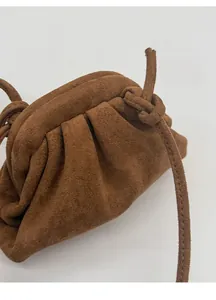 Dettaglio di una borsa a nuvola in camoscio marrone con elegante trama a pieghe e tracolla