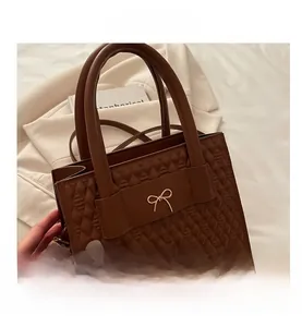 Detail of brown quilted faux leather handbag featuring a gold bow buckle and twin handles