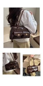 Detail einer dunkelbraunen glänzenden Schultertasche mit Doppeltaschen und Golddrehverschluss