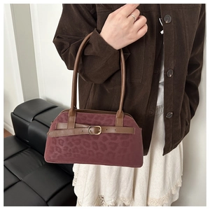 Detail of vintage burgundy shoulder bag with leopard texture and metal buckle on model