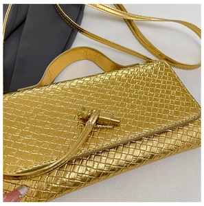 Detail of gold woven handbag featuring a unique metallic knot clasp and thin strap