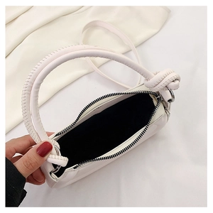 Detail view of cream white faux leather bag with knot handle and smooth metal zipper