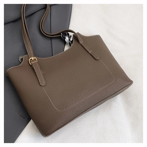Detail of a dark brown lychee leather tote bag with white stitching and decorative silk scarf