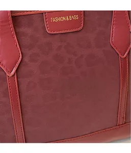 Detail of red tote bag featuring matte suede and glossy leather textures with logo label