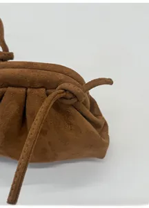 Dettaglio della tracolla allungata con nodo decorativo su una borsa in camoscio marrone