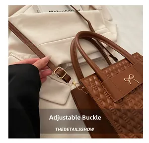 Detailed close-up of the adjustable golden buckle on the brown quilted tote bag