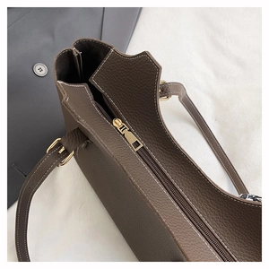 Detailed macro view of dark brown pebbled leather tote with gold zipper and white stitching
