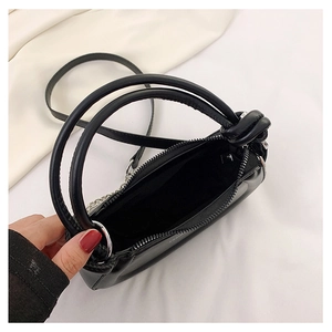 Detail view of the black mini handbag interior with zipper closure and round silver handle