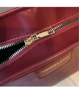 Close-up of golden hardware zipper and fashion leather tag on burgundy tote bag