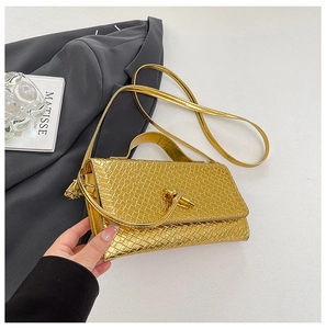 Detail of gold metallic woven texture and rotating metal clasp on a luxury evening handbag