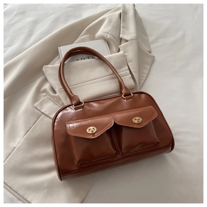 Close-up of a brown leather handbag with gold metal buckles on a neutral background