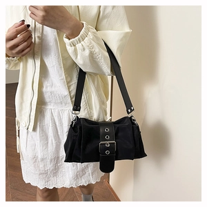Détail du sac à bandoulière en nylon noir avec large sangle en cuir et boucle argent