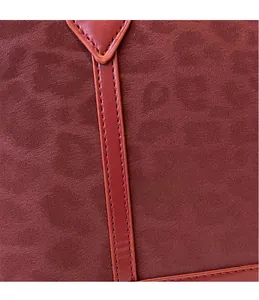 Detailed close-up of precise stitching and high-quality suede texture on a red tote bag