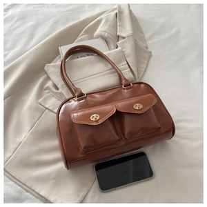 Macro detail of brown leather bag with dual front pockets and gold metallic buckles
