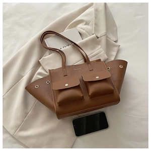 Detailed flat lay of brown litchi leather tote bag with fashion text and front pockets