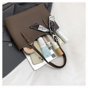 Detail of dark brown tote bag showing large capacity with tablet and silk scarf decoration