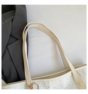 Détail du sac cabas blanc avec motifs d'étoiles argentées et pendentif cœur doré