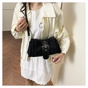 Detail of black matte pleated shoulder bag with oversized silver buckle and thin strap