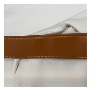 Dettaglio della cintura in pelle marrone con cuciture gialle precise e texture liscia