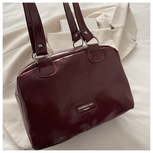 Detail of burgundy glossy leather handbag with silver hardware and logo plaque