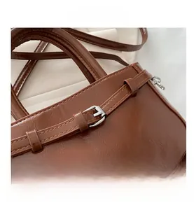 Gros plan d'un sac à main en similicuir marron brillant avec boucle argentée