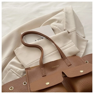 Detailed shot of brown pebble leather tote bag with two gold buckle pockets and fashion logo