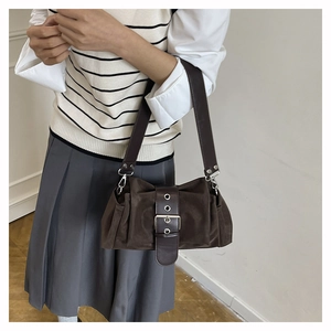 Détail du sac baguette en daim marron foncé avec boucles argentées et sangle vintage