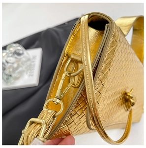 Detail of golden crocodile embossed leather bag with metallic hardware and top handle