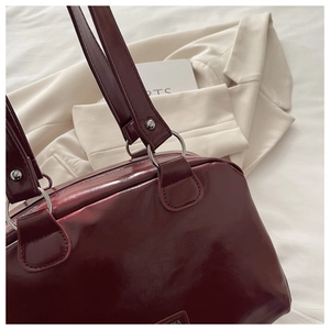 Detail of burgundy leather handbag with silver metallic rings and premium stitching