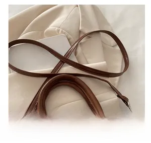 Détail d'un sac à main vintage marron en cuir PU avec bandoulière sur une veste