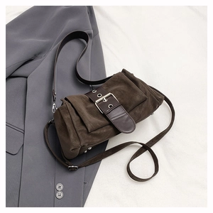 Gros plan du sac bandoulière rétro en daim marron avec boucle vintage sur veste grise