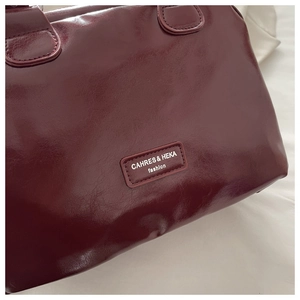 Detail shot of the glossy wine red leather texture and fashion brand lettering