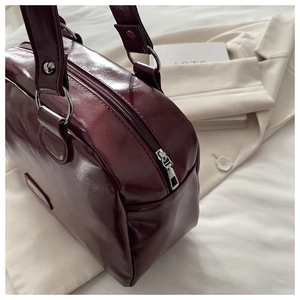 Detail of burgundy PU leather shoulder bag featuring glossy finish and silver hardware