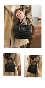 Detail view of black quilted crossbody bag with gold bow clasp on a female model