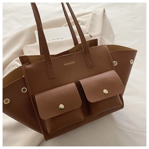 Detailed close-up of dark brown lychee leather tote with front pockets and fashion text