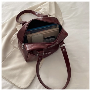 Detail of burgundy vintage tote bag showing large capacity with books and phone inside