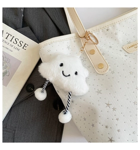 Détail d'un charme de nuage en peluche blanche avec sourire sur un sac fourre-tout