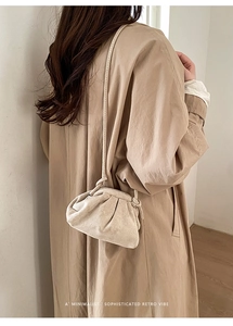 Detail view of a beige pleated dumpling bag with matte texture on a model's shoulder