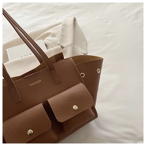 Detail of brown lychee leather tote bag with gold buttons and front pockets