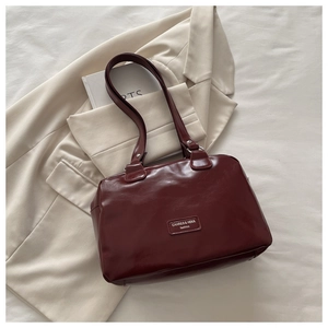 Flat lay of a burgundy faux leather tote bag on beige fabric and fashion clothing