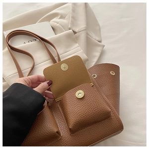 Detail of metal magnetic buckle and pebble leather texture on a brown tote bag