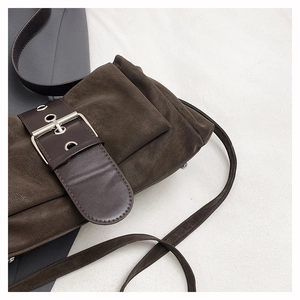 Détail d'un sac à bandoulière en daim marron foncé avec boucle métallique et ceinture punk
