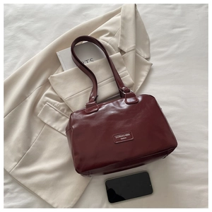 Close-up of burgundy wax leather shoulder bag with logo on a stylish beige blazer