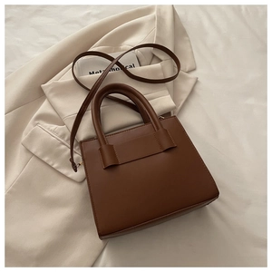 Vista dall'alto di una borsa tote minimalista in pelle marrone con manici e tracolla