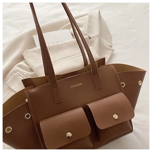 Detailed macro of brown lychee grain leather tote with front flap pockets and gold hardware
