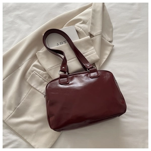 Detail of burgundy waxed leather tote bag on a blazer, showing texture and straps