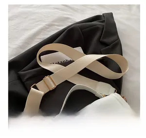 Close-up of wide woven shoulder strap with gold metal buckle on cream crossbody bag