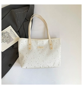 Détail du sac cabas blanc avec motif d'étoiles et étiquette du logo CAHRES & HEKA