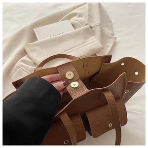 Detail of brown litchi leather tote bag showing gold magnetic closure and pocket texture