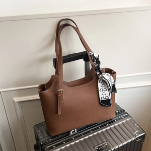 Brown lychee leather tote bag with silk scarf on a suitcase for daily travel